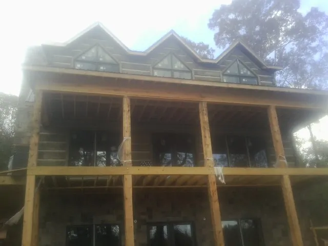 Dormers and porch framing on a large log home under construction — Roof Coating work by our crew in Haw River