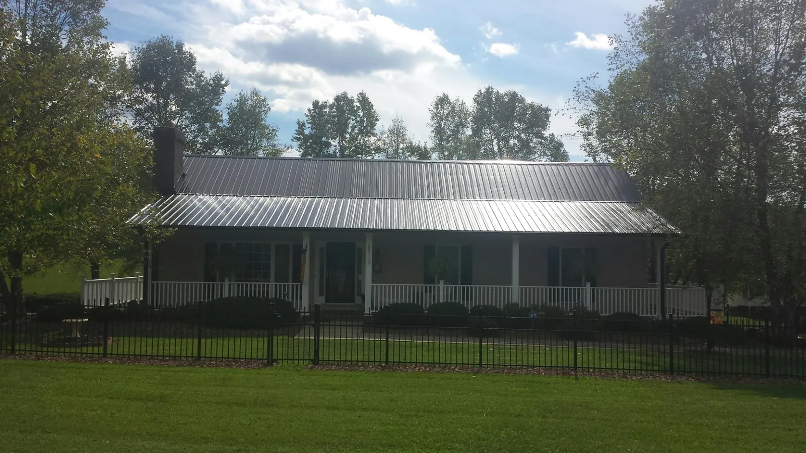 Gray metal roof on a brick ranch with a full width front porch — Gutter Guard Installation work by our crew in Haw River
