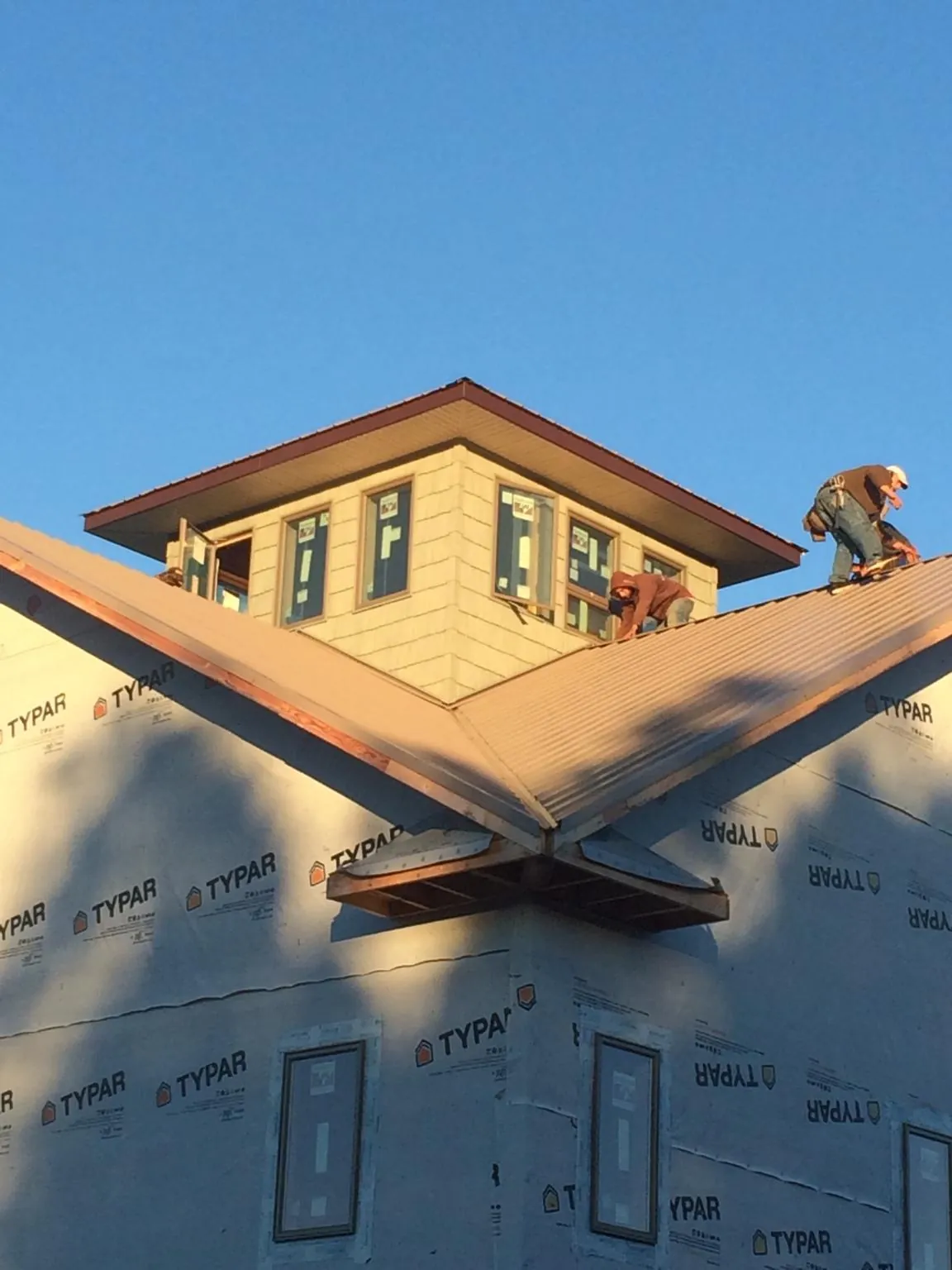 Roofers working around a rooftop cupola on a new metal roof at sunset — Roof Waterproofing in Haw River by Roofing Brothers